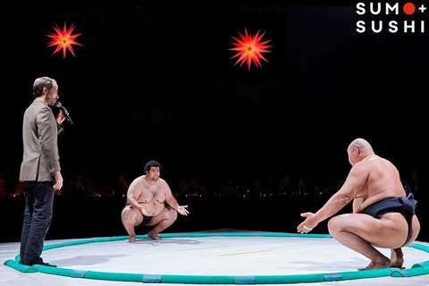 Ramy Elgazar and an opponent squaring off in the ring with a host at a Sumo and Sushi arena show