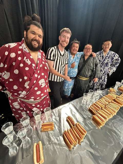 Ramy Elgazar in a polka dot robe with Nick DiGiovanni and guests at a hot dog shoot