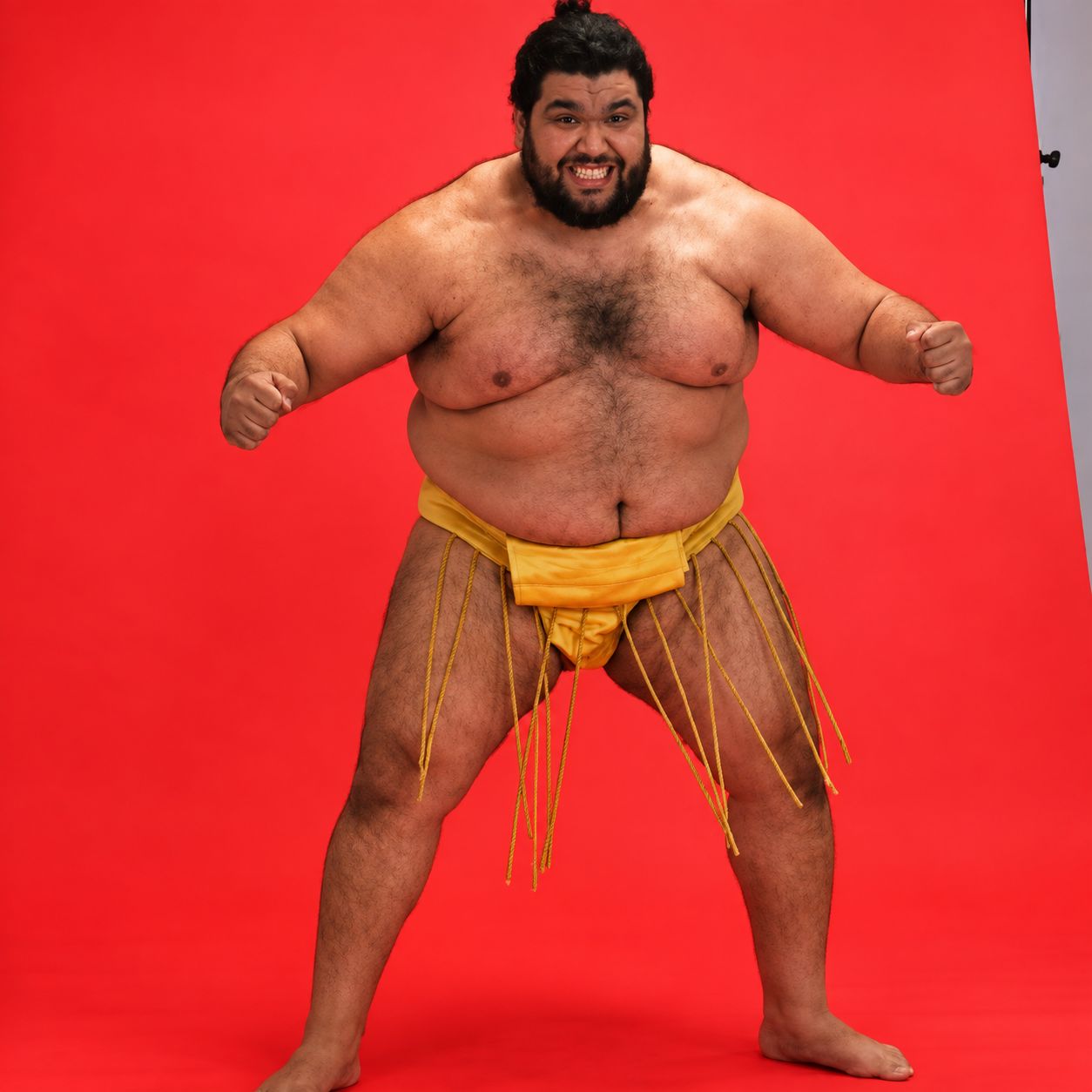 Ramy Elgazar in a sumo mawashi posing against a red studio backdrop