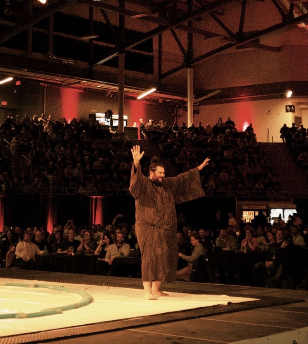 Ramy Elgazar in a ceremonial robe entering the sumo ring before a packed arena